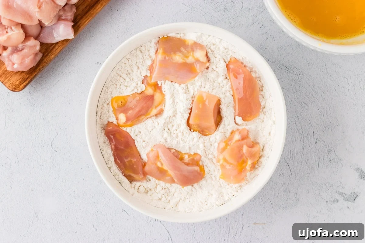Raw chicken pieces fully coated in the gluten-free flour and cornstarch mixture.