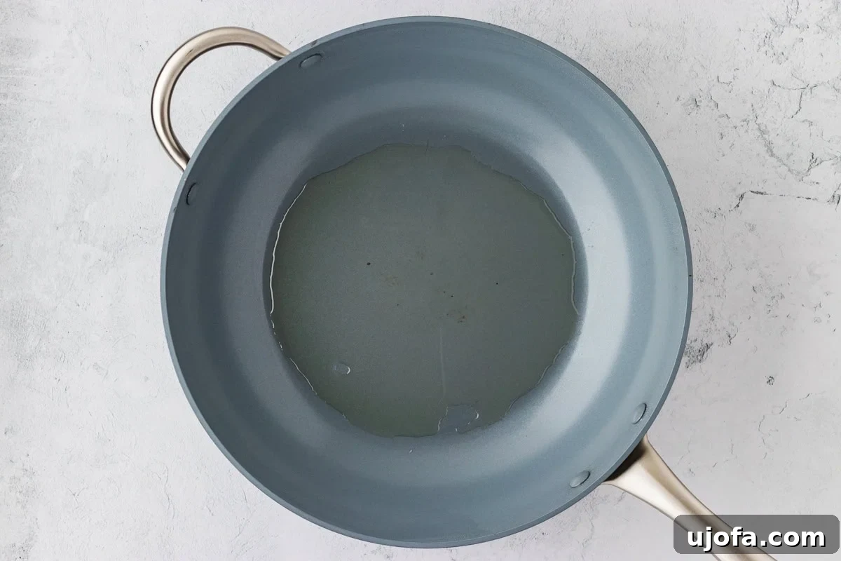Overhead view of a frying pan with cooking oil heating up, showing readiness for frying.
