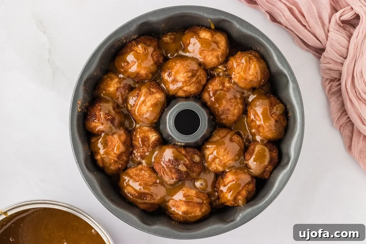 Gooey Gluten-Free Monkey Bread Indulgence 14 A bundt cake pan filled with layers of monkey bread dough balls and covered with a generous pour of caramel sauce.