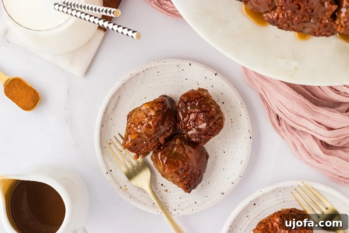 Gooey Gluten-Free Monkey Bread Indulgence 16 Three pieces of gluten-free monkey bread on a white speckled plate with a gold fork, ready to be enjoyed.