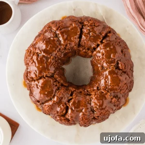 Overhead view of a freshly baked gluten-free monkey bread on a white cake platter, glistening with caramel.