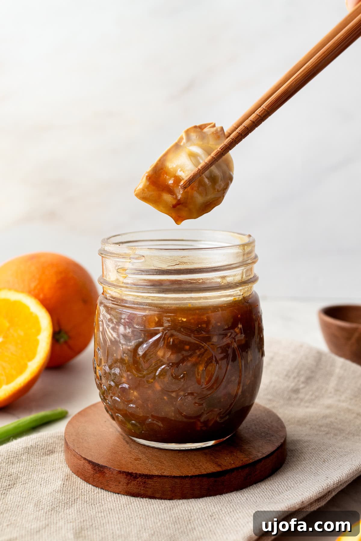 Golden Orange Reduction 2 Homemade orange reduction sauce in a mason jar with a dumpling being dipped in with chopsticks.