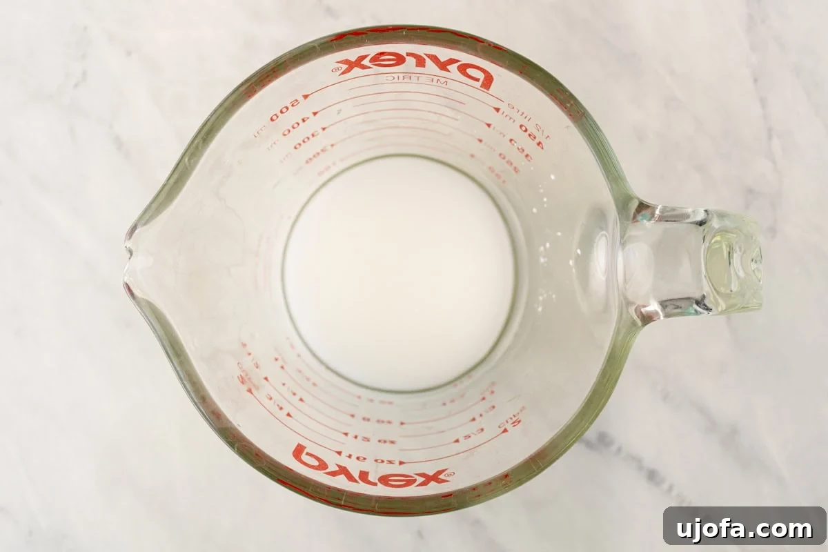 Golden Orange Reduction 11 A clear glass measuring cup containing a smooth cornstarch slurry, ready for thickening.