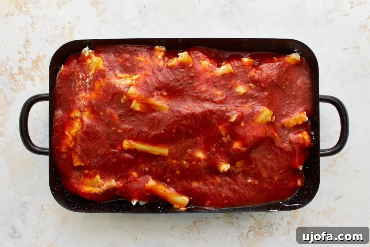 Comforting Gluten-Free Ziti Bake 12 gluten-free ziti in black baking dish covered in marinara sauce