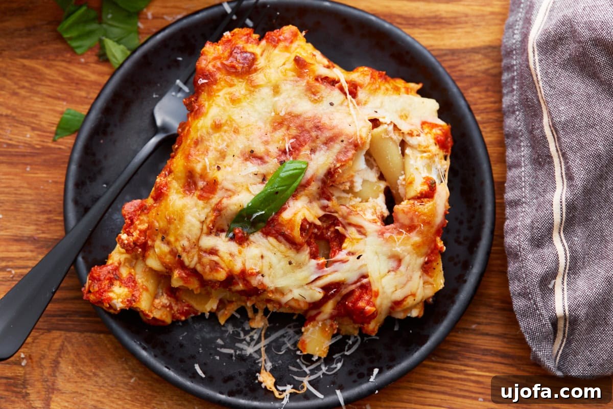 Comforting Gluten-Free Ziti Bake 7 piece of gluten-free baked ziti on a black plate with a black fork next to a gray rag