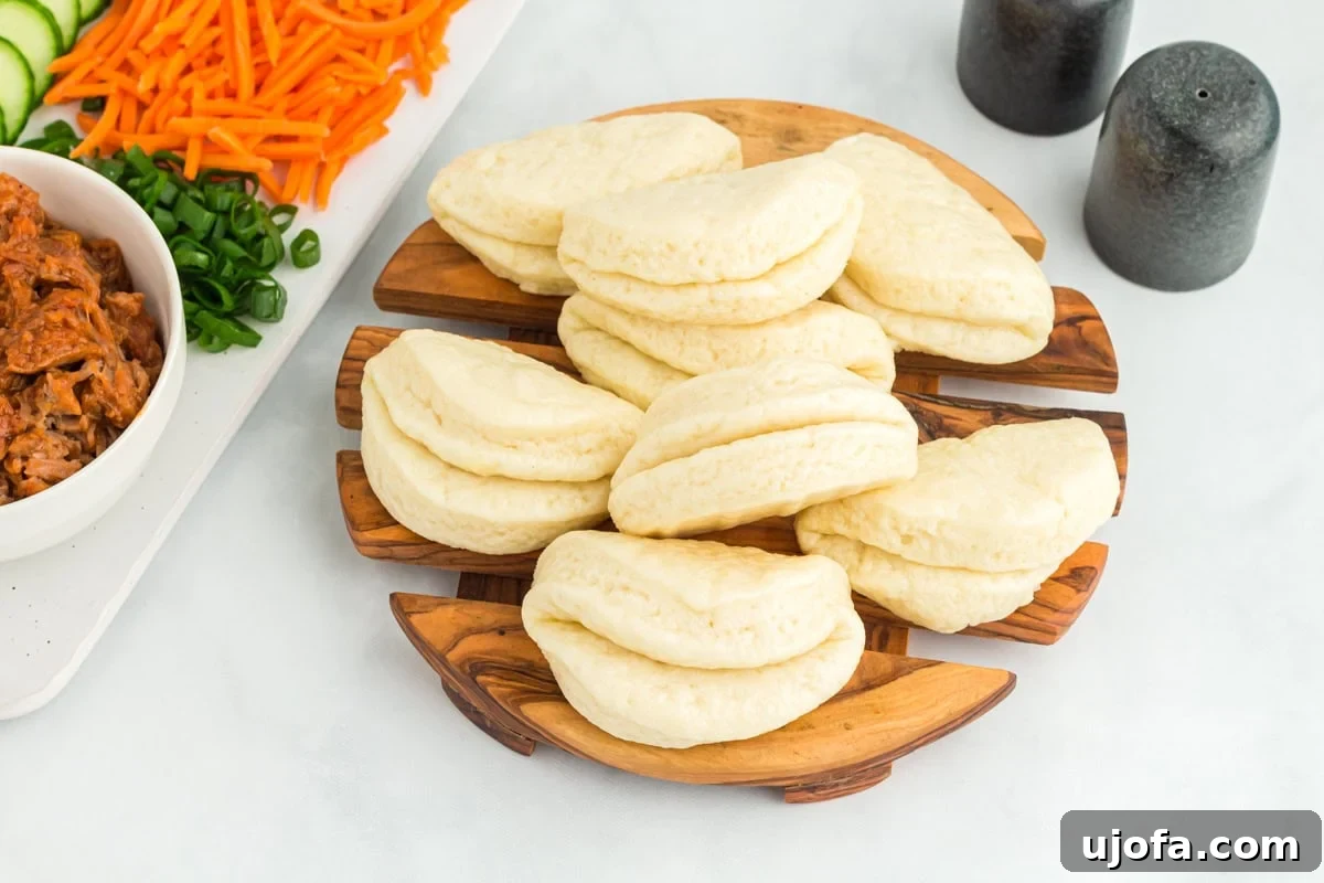 A delightful stack of warm, fluffy gluten-free bao buns piled on top of each other on a rustic circular wooden cutting board, showcasing their perfect texture.