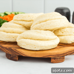5 gluten-free bao buns stacked on a round wooden cutting board