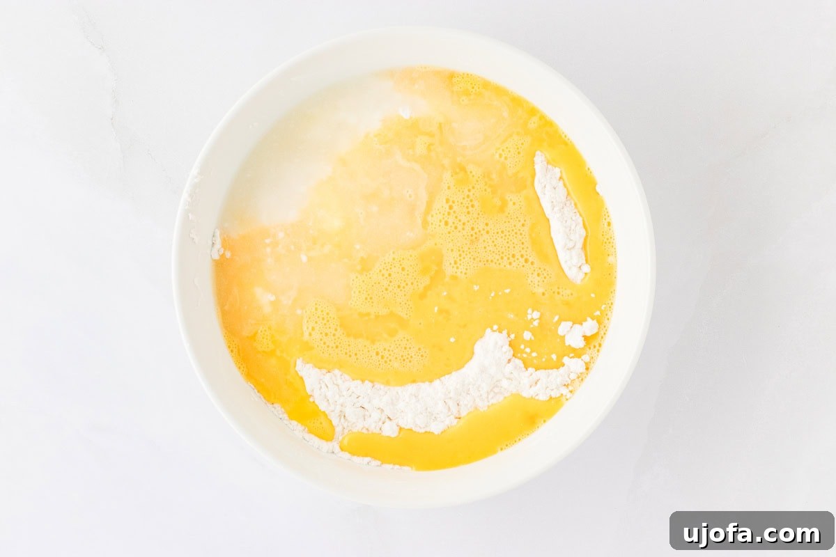 Guilt-Free Crispy Egg Rolls 12 Gluten-free flour mixture in a white bowl, with three whisked eggs and a small amount of warm water added to the center.