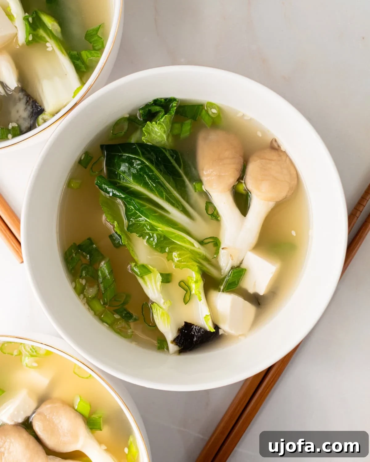 gluten-free miso soup in a white bowl with bok choy and mushrooms and chopsticks next to the bowl