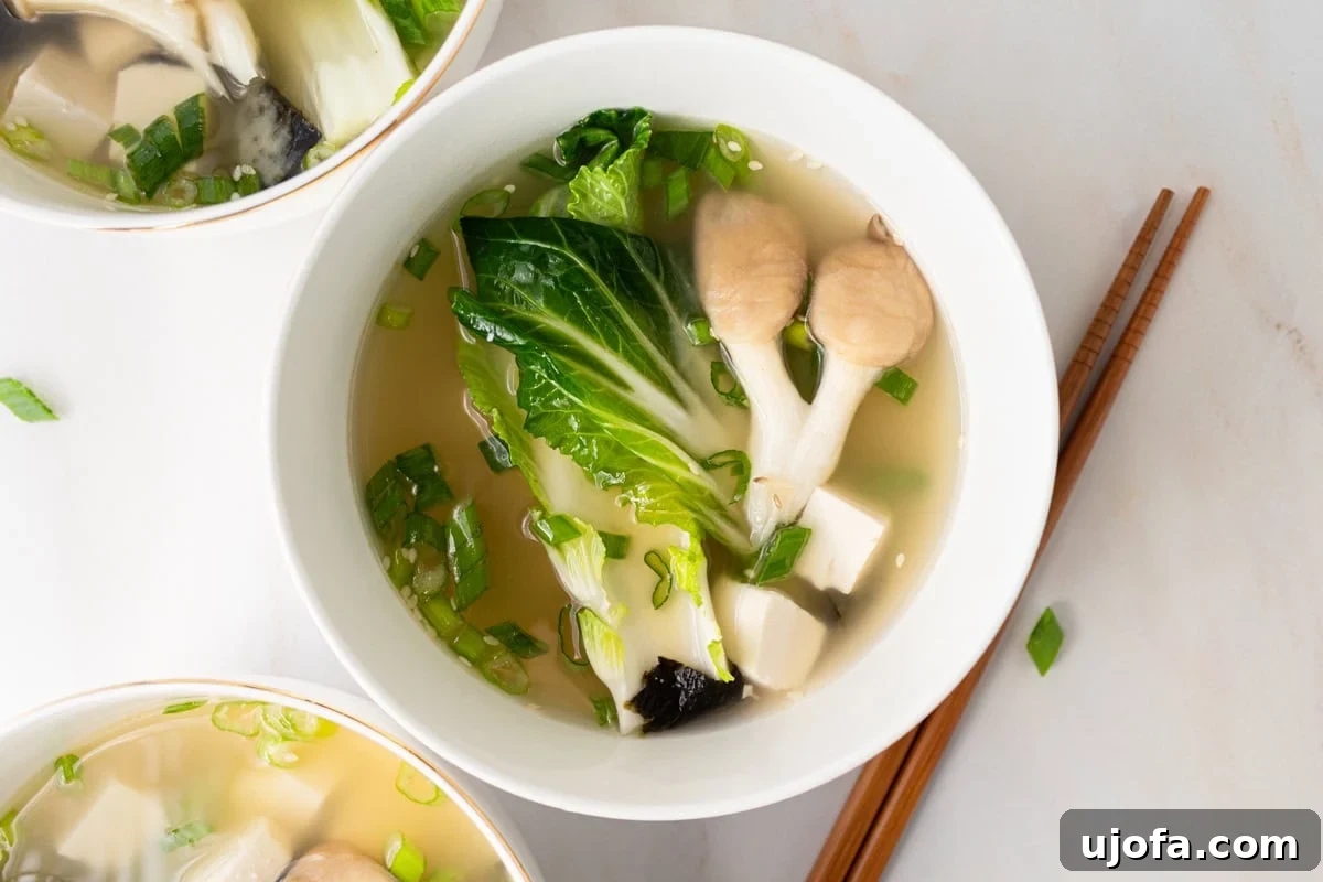 horizontal shot of gluten-free miso soup in white bowl with chopsticks next to it