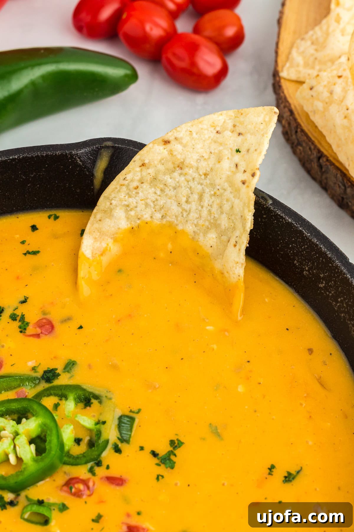 Creamy Vegan Queso 5 tortilla chip being dipped into vegan queso in black skillet