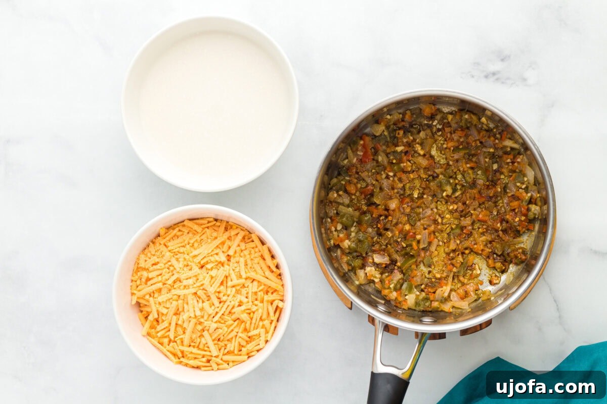 Creamy Vegan Queso 9 sauteed onions, bell pepper, jalapeños, and garlic in stainless steel pot next to bowl with shredded cheese and bowl with coconut milk