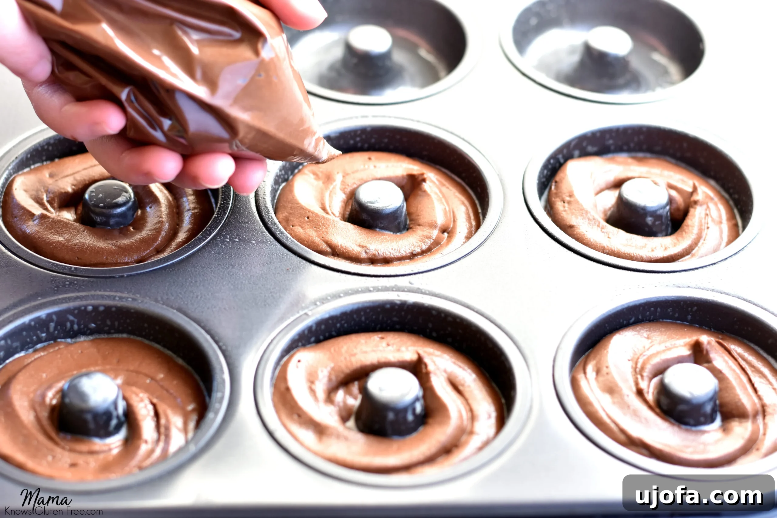 Gluten-free chocolate donut batter being piped precisely into a donut pan, ensuring perfectly formed treats.