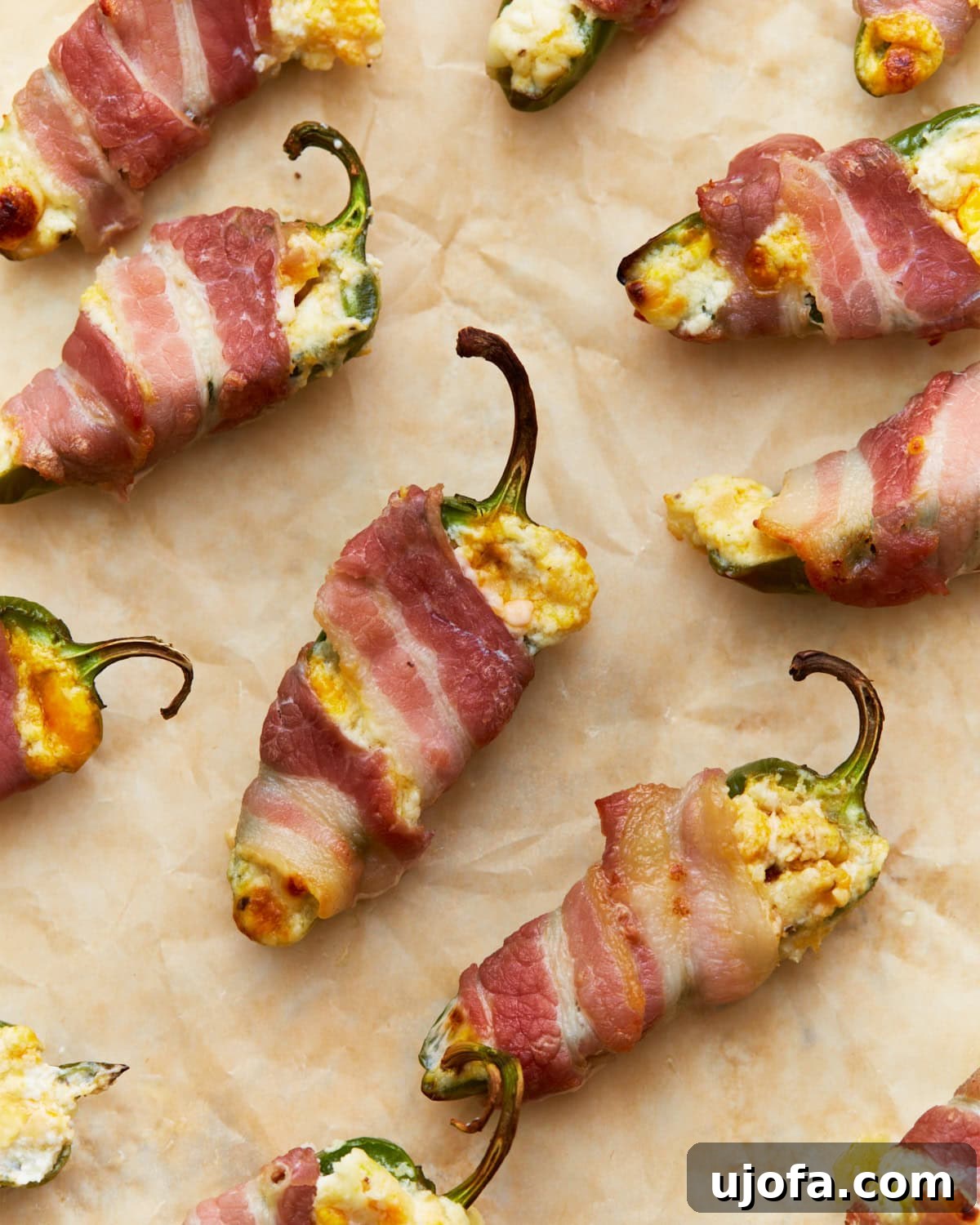 Baked keto jalapeño poppers, filled with creamy cheese and wrapped in crispy bacon, on parchment paper, ready to be served warm.