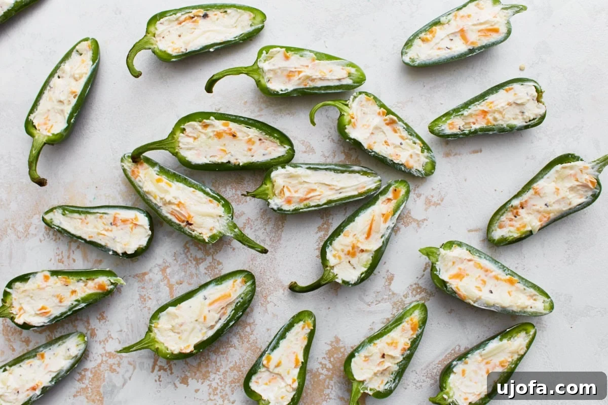 Several jalapeño halves, perfectly stuffed with a generous amount of creamy cheese filling, laid out neatly before being wrapped.