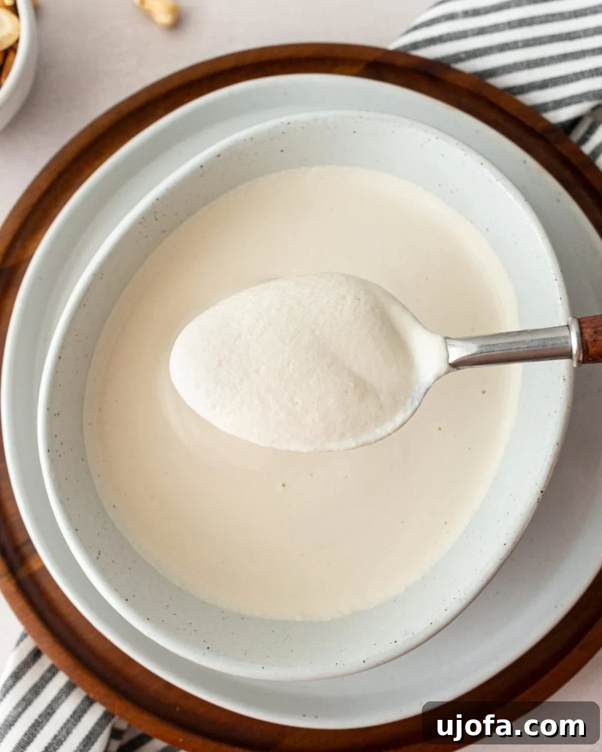 A spoonful of creamy cashew cream being held above a bowl, highlighting its rich and velvety consistency