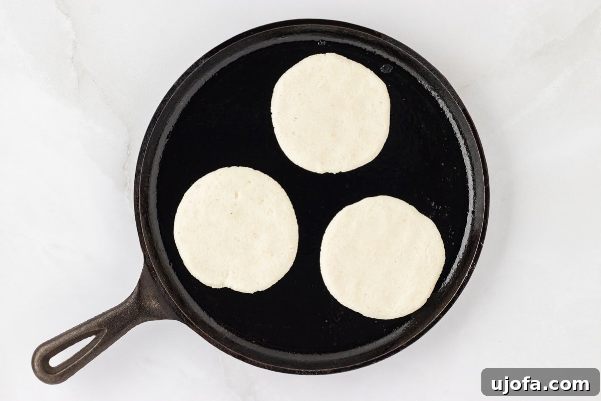 Crafting Perfect Arepas 10 3 arepa dough circles on an oiled black skillet.