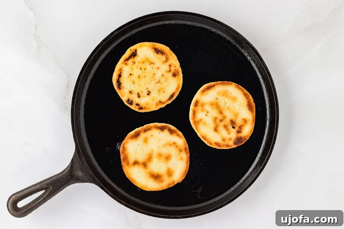 Crafting Perfect Arepas 11 3 golden brown arepas on an oiled black skillet.
