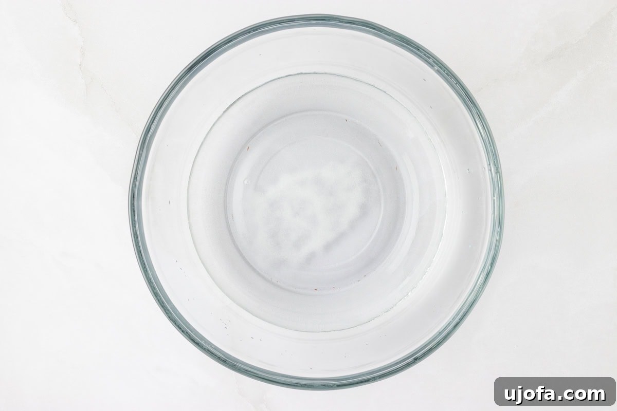 Crafting Perfect Arepas 4 Salt water mixture in a glass bowl on a white surface.