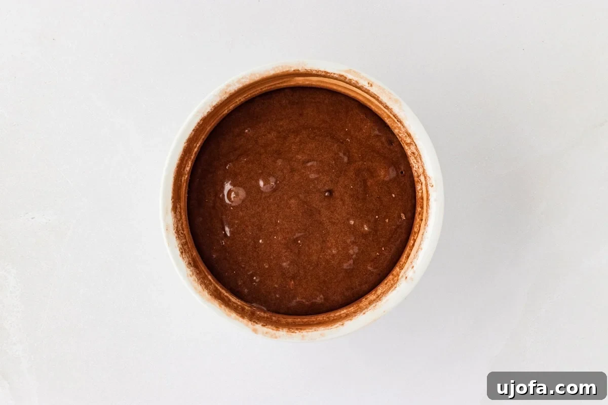 Molten Gluten Free Chocolate Bliss 12 Dusted white ramekin filled with gluten-free chocolate lava cake batter, ready for baking.