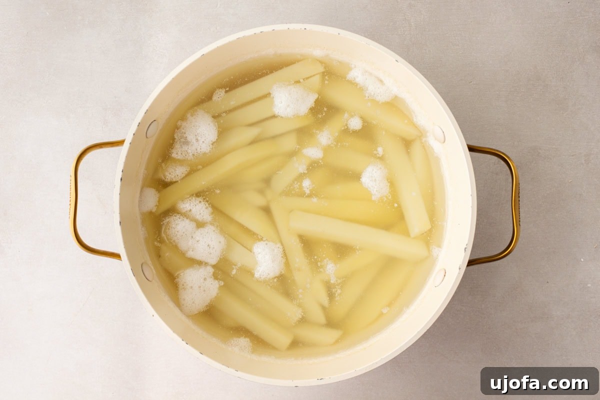 French fries soaking in boiling water in a large white pot