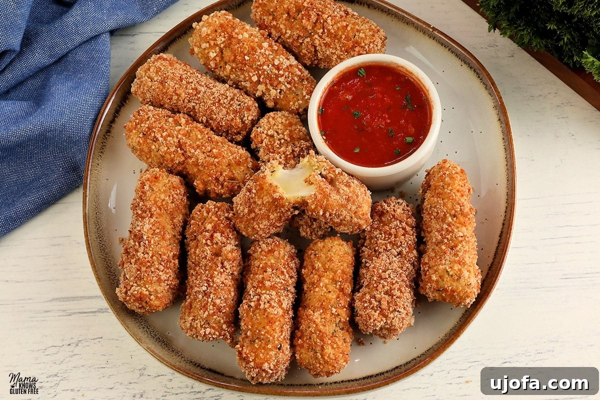 gluten-free mozzarella sticks on a white plate with one broken open to see the melted cheese