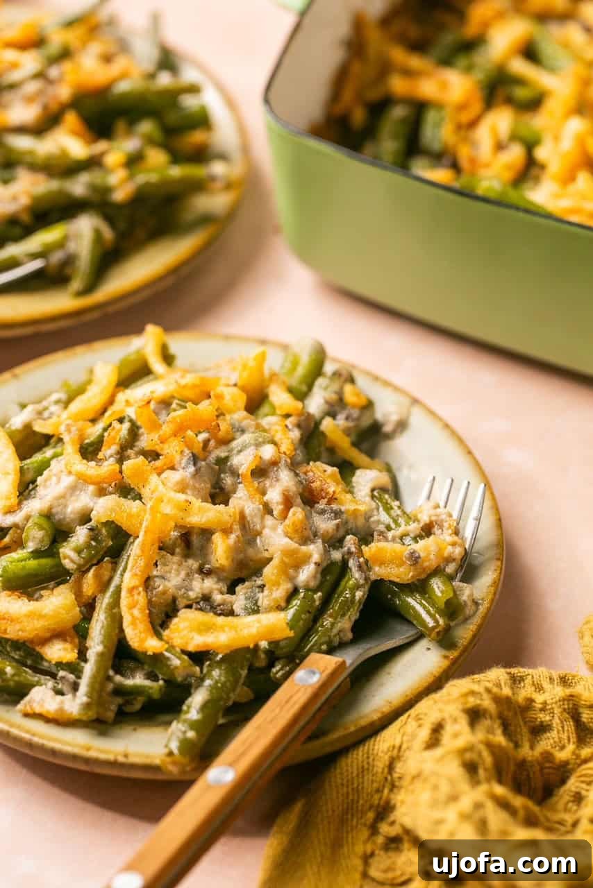 a close up shot of green beans and fried onions on a plate with a fork 