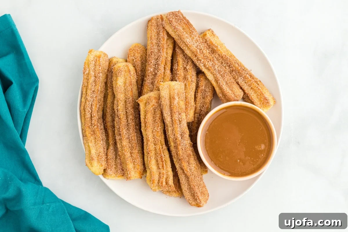 Delectable Gluten-Free Churros 13 A mouth-watering plate of cinnamon sugar-coated gluten-free churros, artfully arranged with a small bowl of caramel dipping sauce.