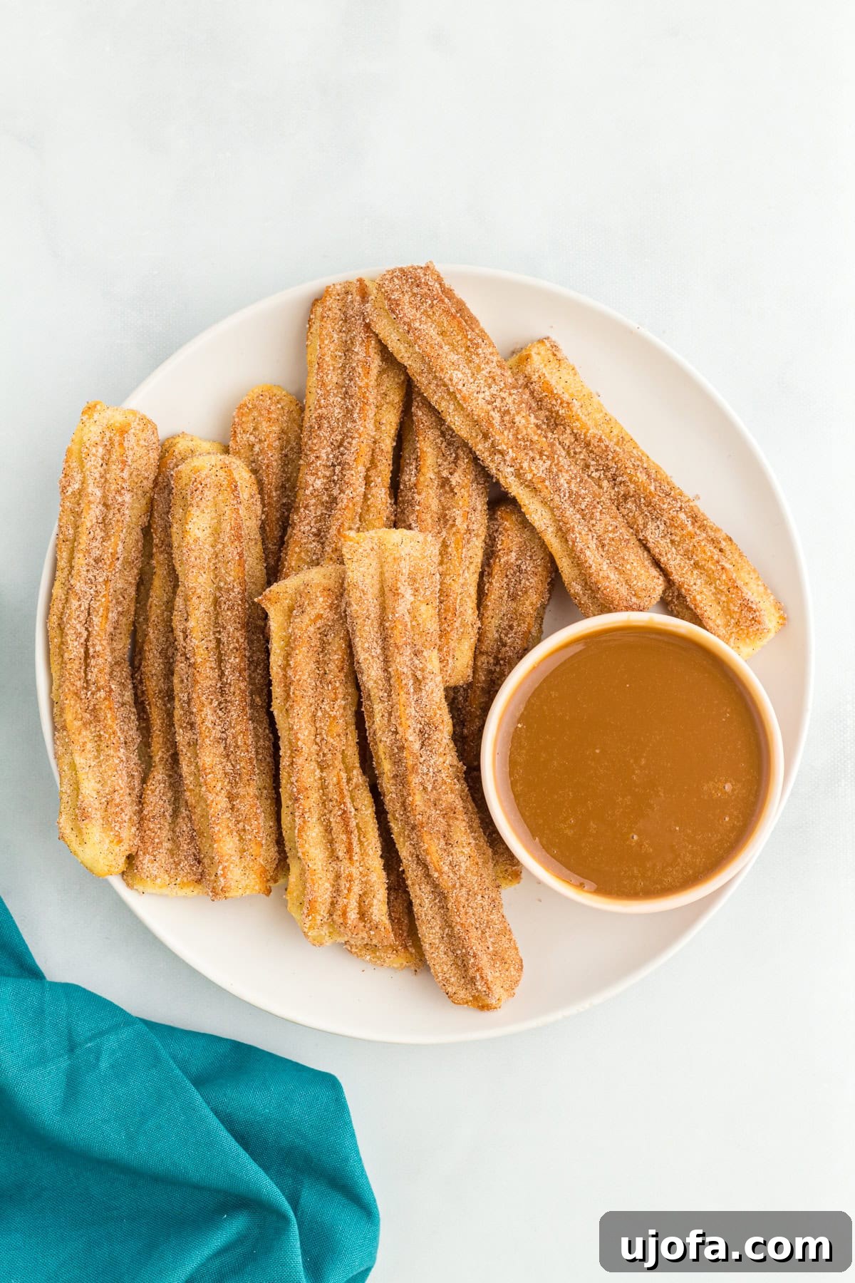 Delectable Gluten-Free Churros 15 A elegantly presented plate of gluten-free churros, perfectly coated in cinnamon sugar, accompanied by a small pot of creamy caramel dipping sauce.