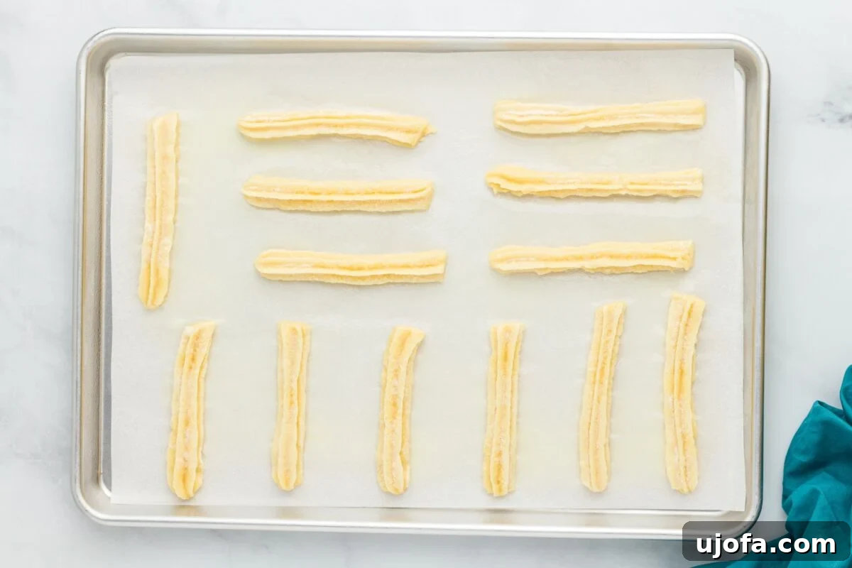 Delectable Gluten-Free Churros 8 Neatly piped gluten-free churros arranged in rows on a parchment-lined baking sheet, awaiting their turn in the oven.