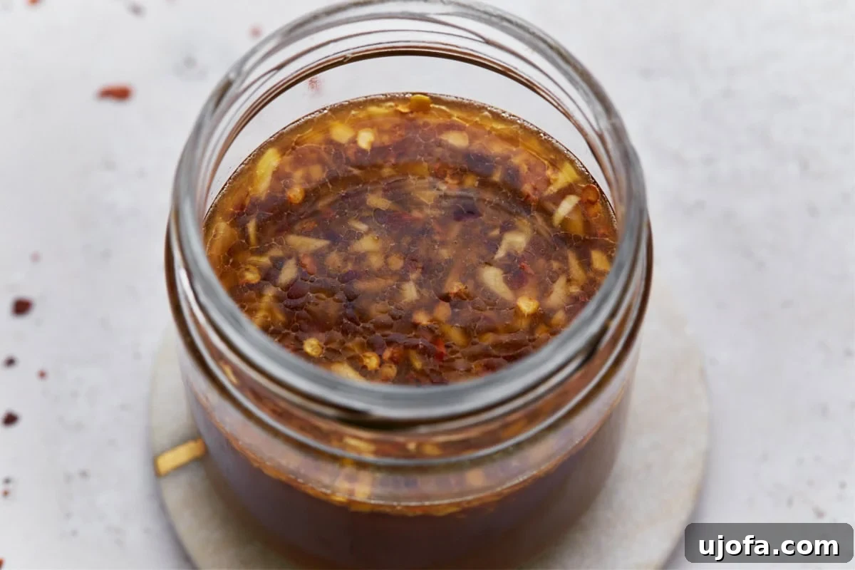 Delicious Gluten-Free Stir Fry Enhancer 7 A close-up of gluten-free stir-fry sauce in a jar, highlighting the garlic, chili flakes, and glossy liquid that make the sauce appealing