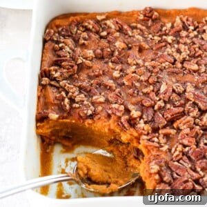 A close-up of a serving of the paleo sweet potato casserole with a generous portion of the crunchy pecan topping in a white dish.