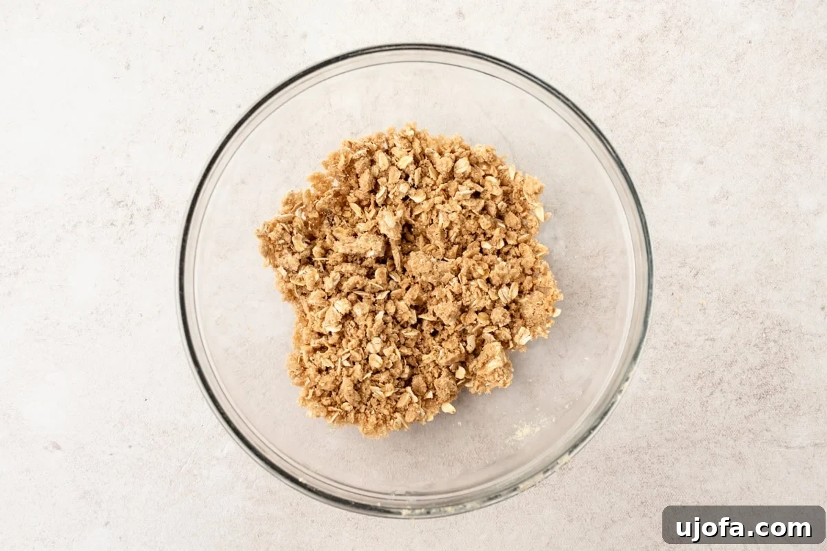 A clear glass bowl filled with prepared crumbly streusel topping for muffins.