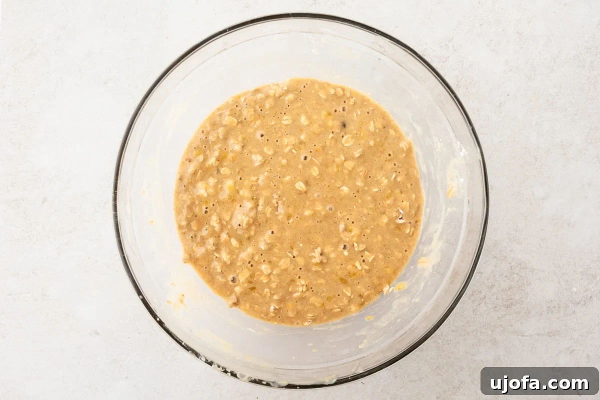 A glass bowl of banana oatmeal muffin batter, fully mixed and ready to be portioned.