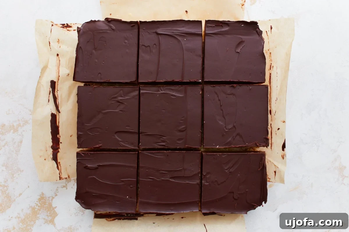 The fully assembled gluten-free millionaire shortbread cut into neat squares on parchment paper, showcasing the chocolate, caramel, and shortbread layers.