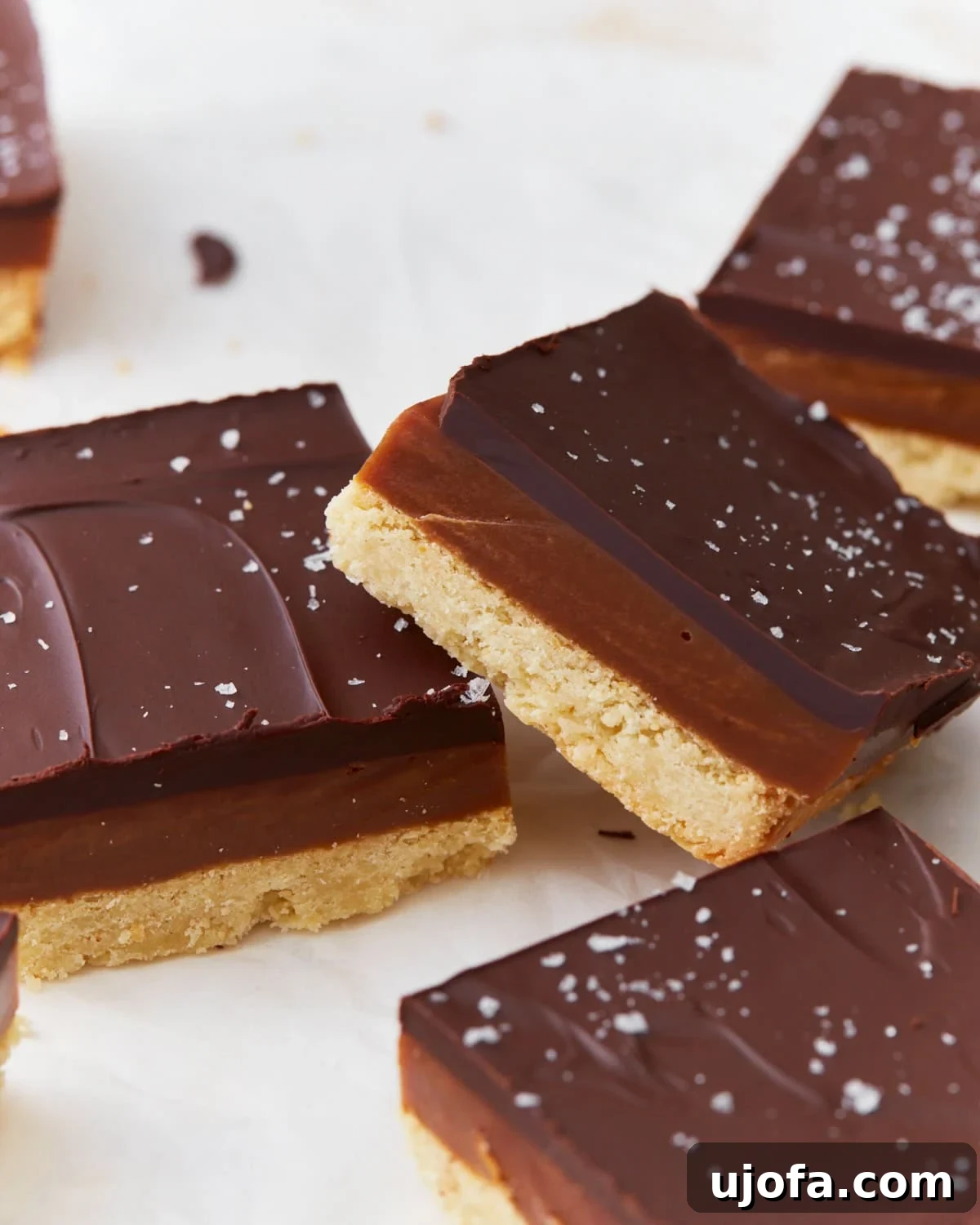 A stack of two gluten-free millionaire shortbread slices showing the distinct layers of chocolate, caramel, and shortbread.
