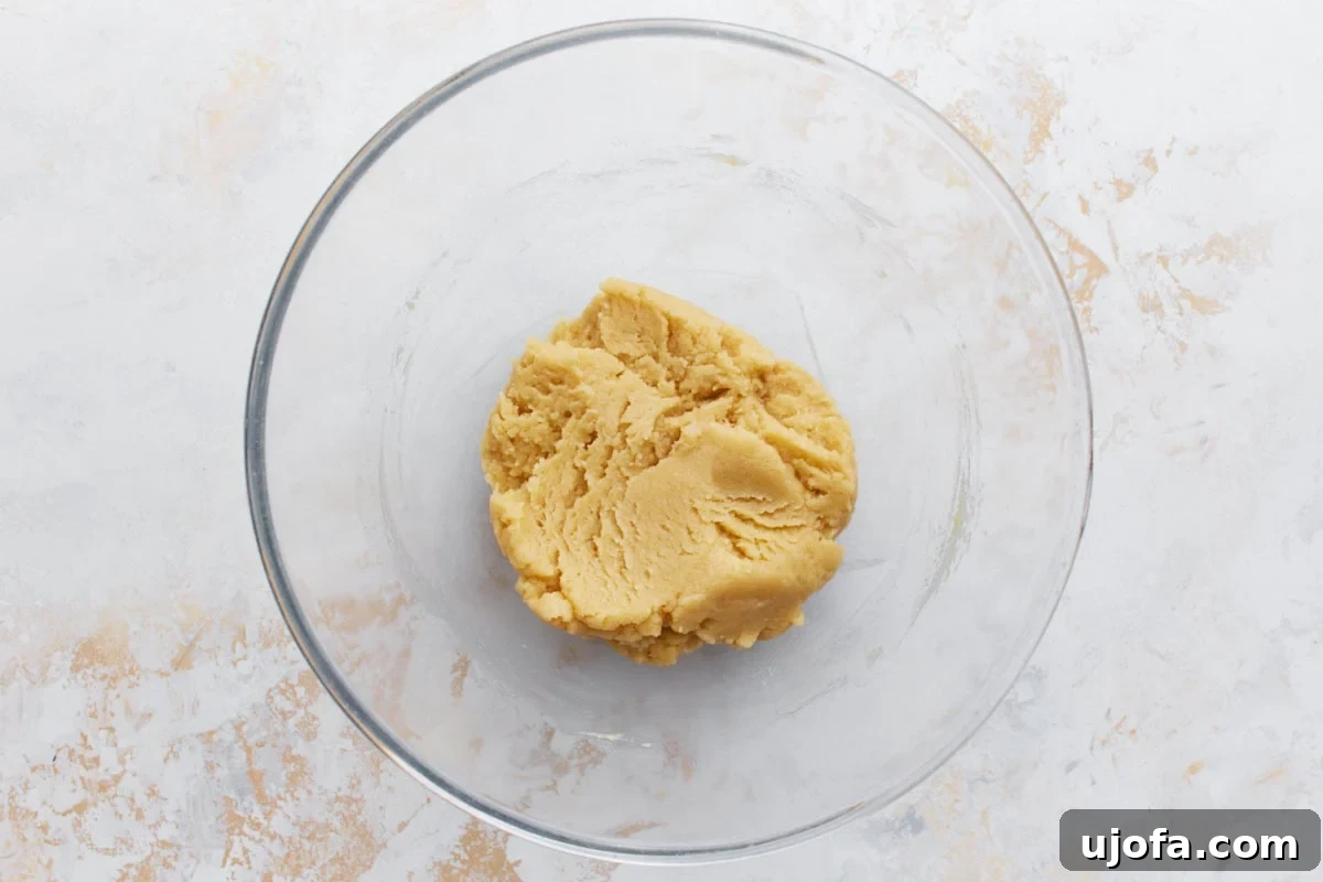 A glass mixing bowl with creamy gluten-free shortbread dough, ready to be pressed into a baking pan.