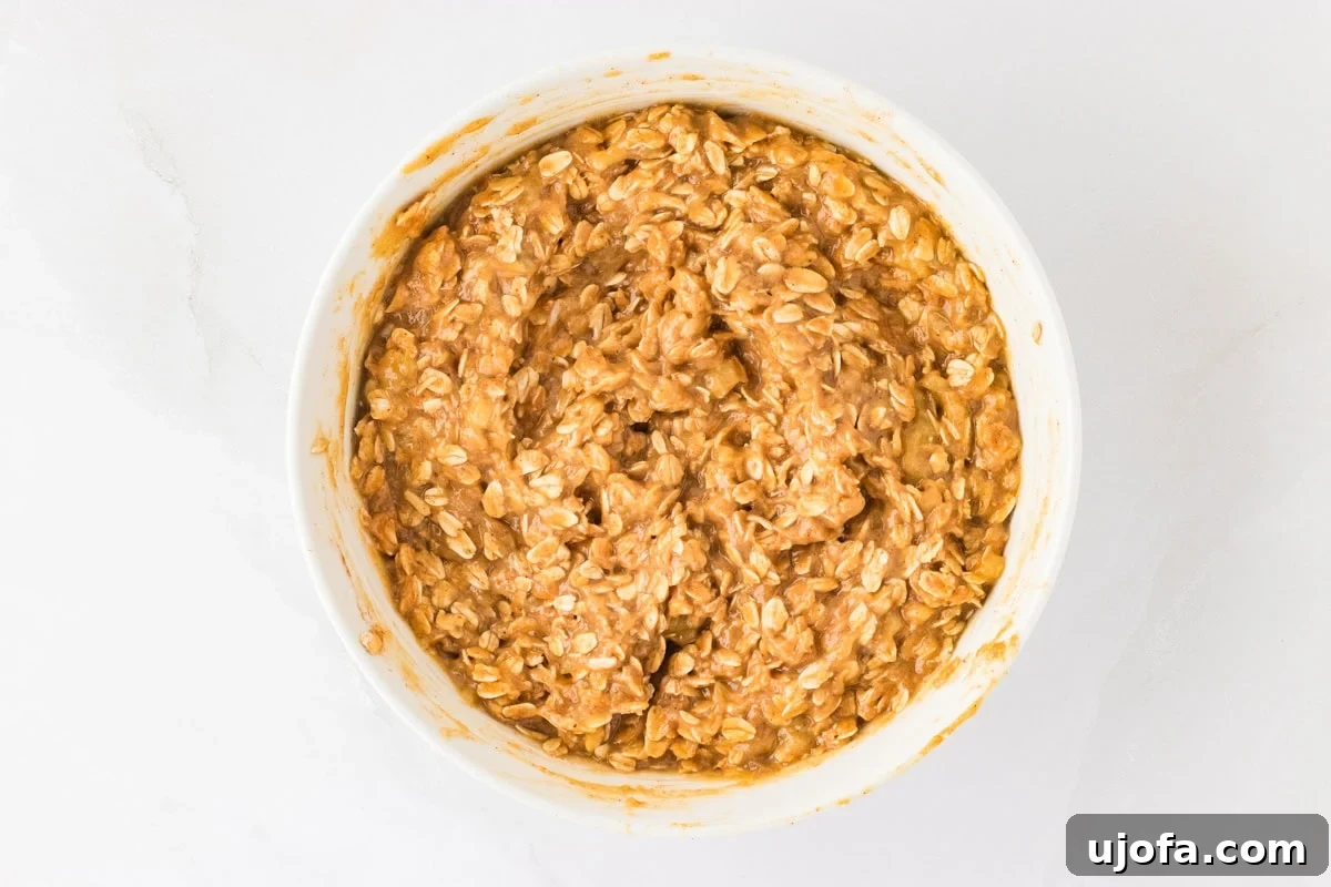 Golden Banana Oat Bars 9 The mixed batter for banana oatmeal bars, thick and hearty, showcasing the oats and creamy peanut butter.