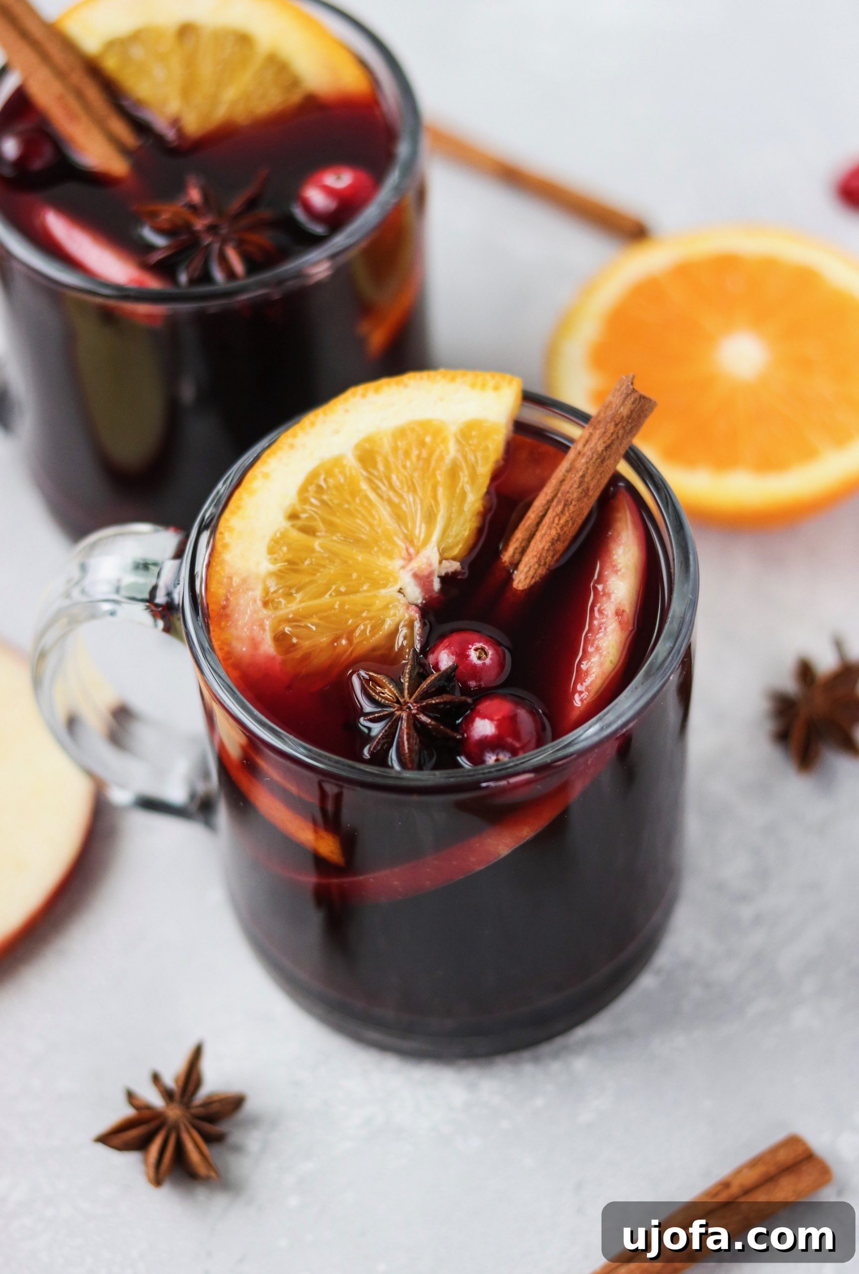 Homemade Mulled Wine: Quick Stovetop or Slow Cooker Simmer 4 Multiple cute mugs filled with Mulled Wine, garnished with orange and cranberries.