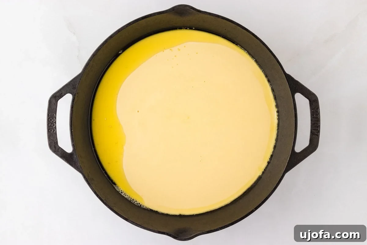 Golden Socca Chickpea Flatbread 10 Socca batter poured into a preheated cast iron skillet, forming an even layer ready for baking.