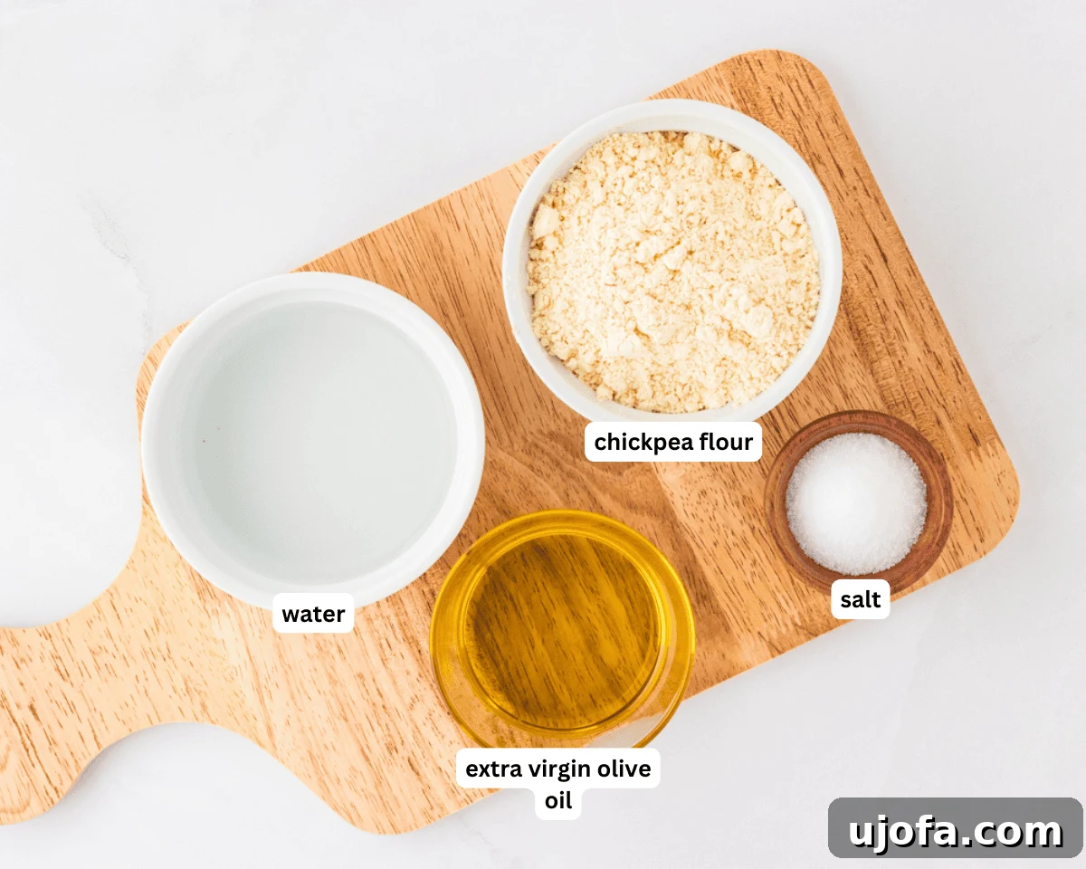 Golden Socca Chickpea Flatbread 4 Socca (chickpea flatbread) ingredients: chickpea flour, olive oil, salt, and water arranged on a wooden board.