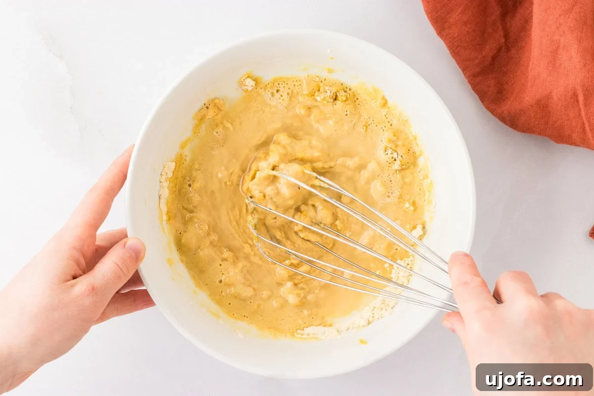 Golden Socca Chickpea Flatbread 6 Chickpea flour mixed with water, olive oil, and spices in a bowl, being whisked into a smooth batter.