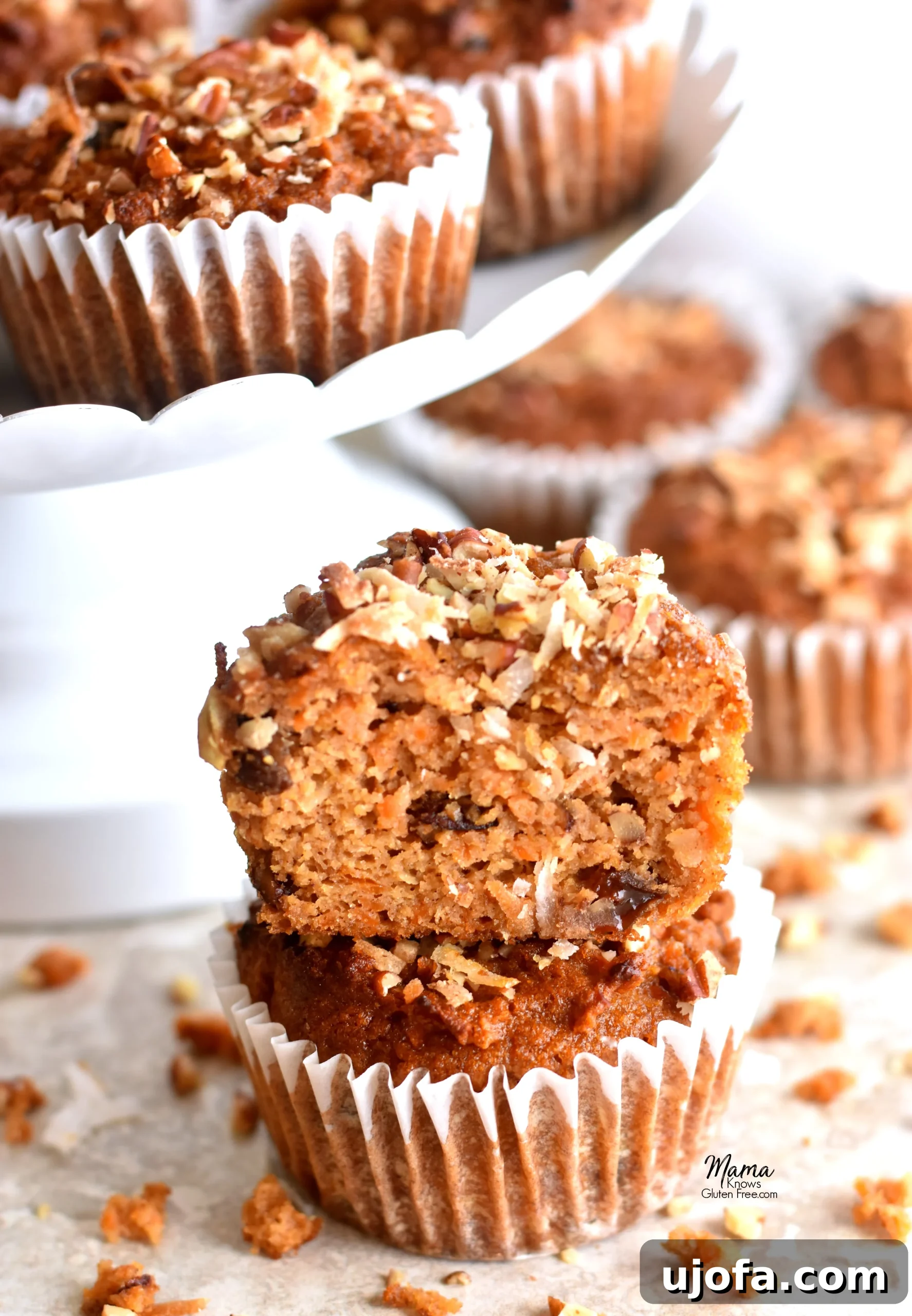 Wholesome Paleo Carrot Cake Muffins 4 A close-up shot of a Paleo carrot cake muffin sliced in half, revealing its moist interior, generously speckled with shredded carrots, plump raisins, and crunchy pecans, resting on other whole muffins.