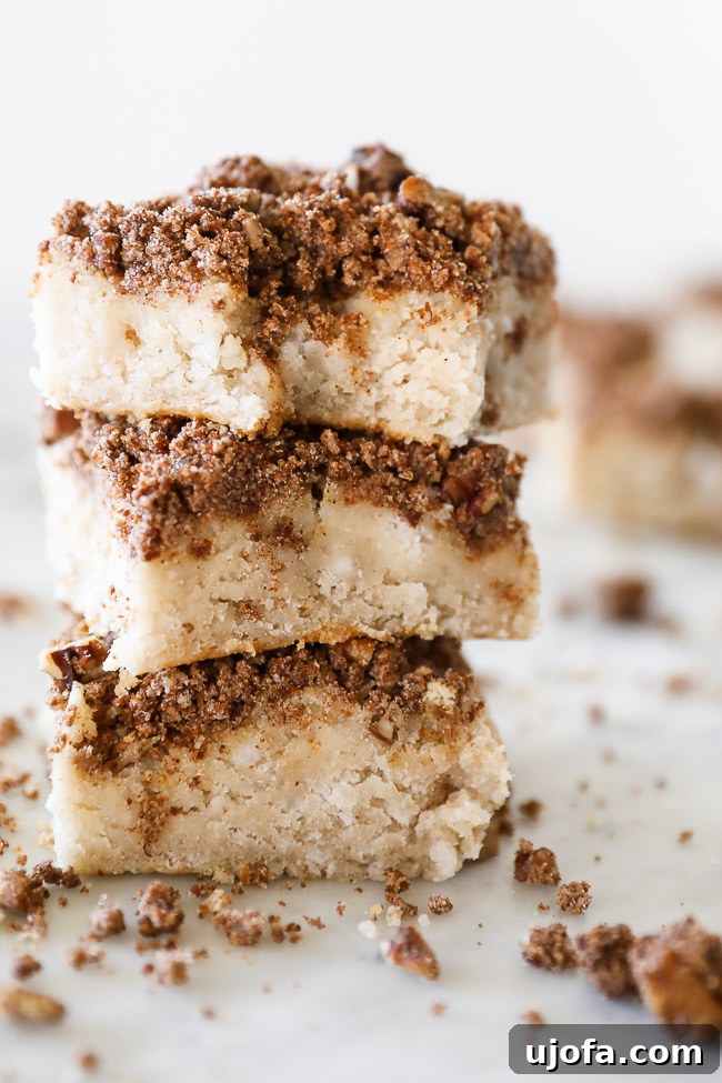 A beautifully textured gluten-free coffee cake with a generous crumb topping, served on a rustic wooden board.