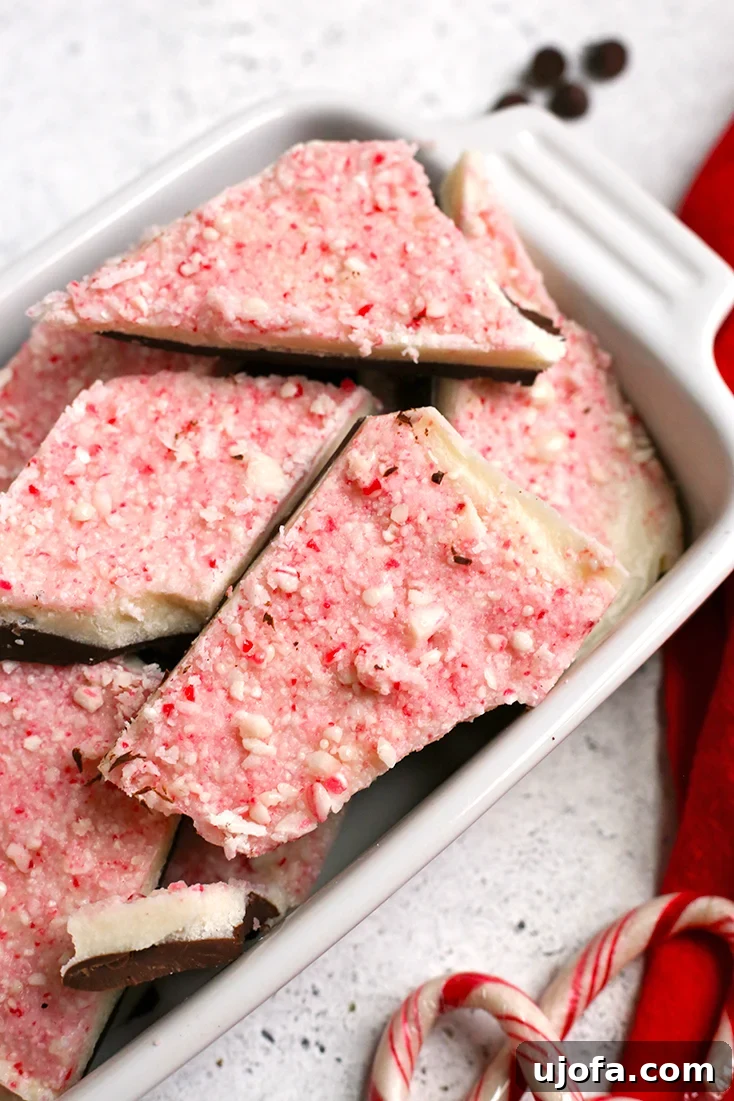 Festive paleo peppermint bark, featuring layers of dark and white chocolate, adorned with crushed peppermint pieces.