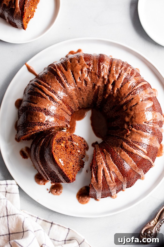 A moist and aromatic paleo gingerbread bundt cake, dusted with powdered sugar and adorned with festive garnishes.