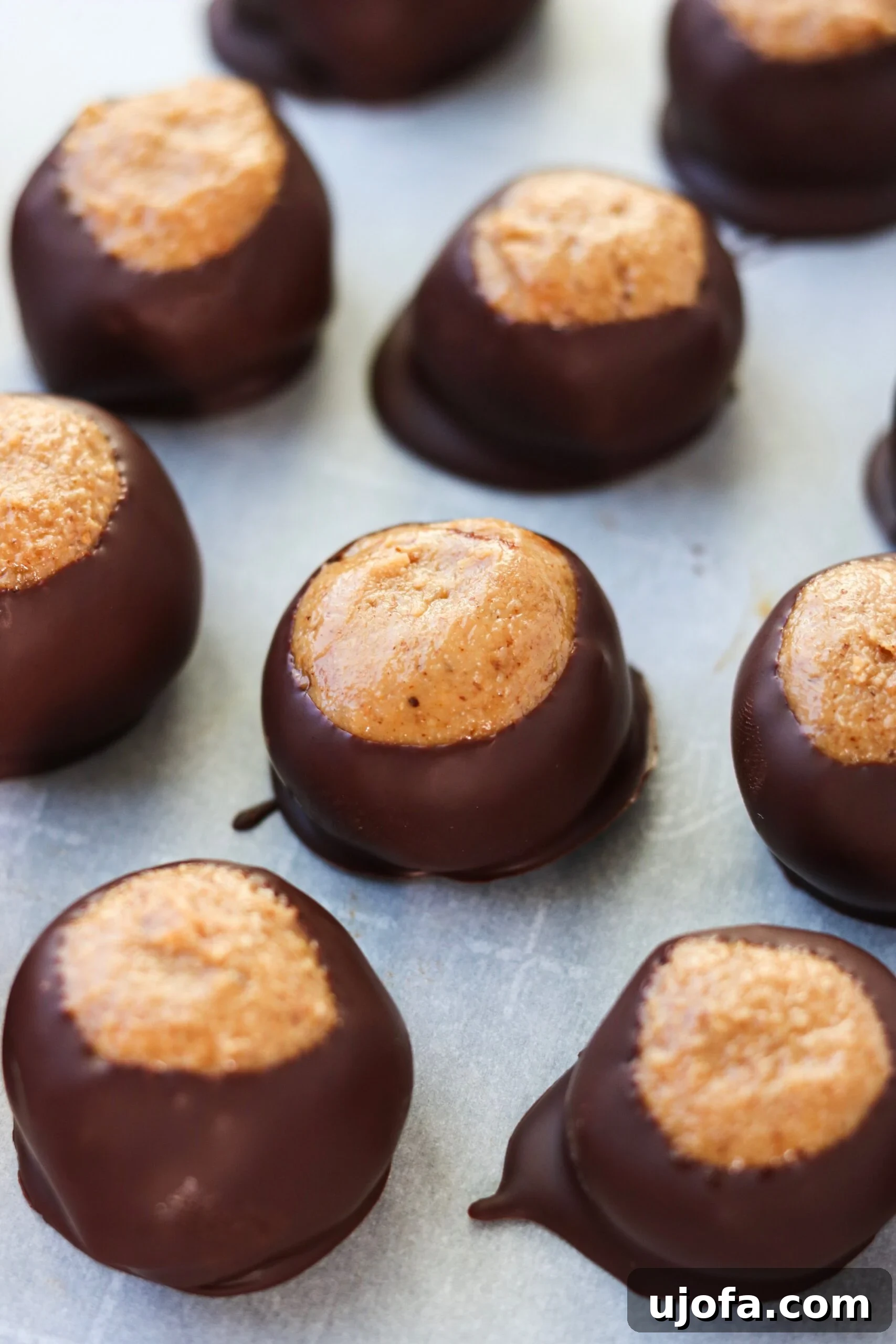 Close-up of a Paleo Buckeye Ball, showcasing its smooth chocolate coating and a glimpse of the creamy, golden interior.