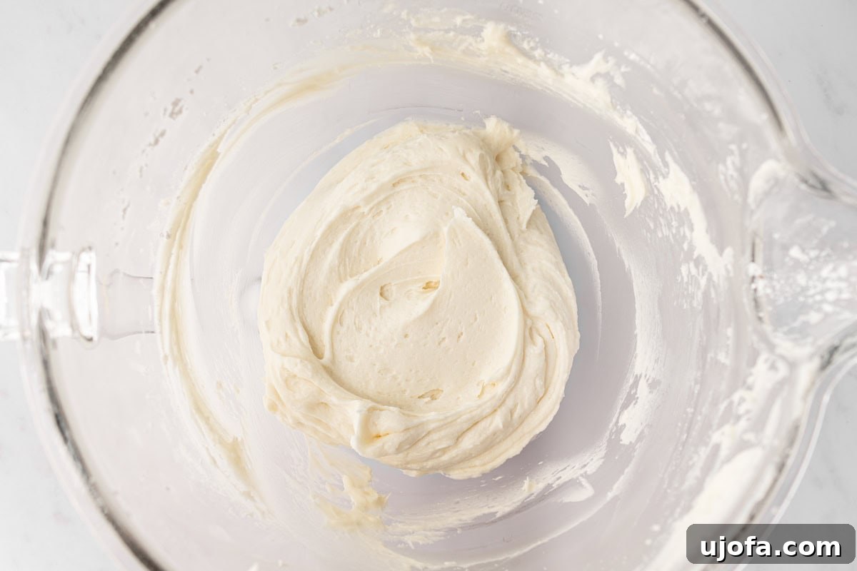 A mixing bowl filled with fluffy cream cheese frosting, showing a smooth, creamy texture.