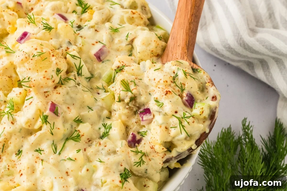 A wooden spoon scooping gluten-free potato salad from a serving bowl, highlighting the texture of the dish.