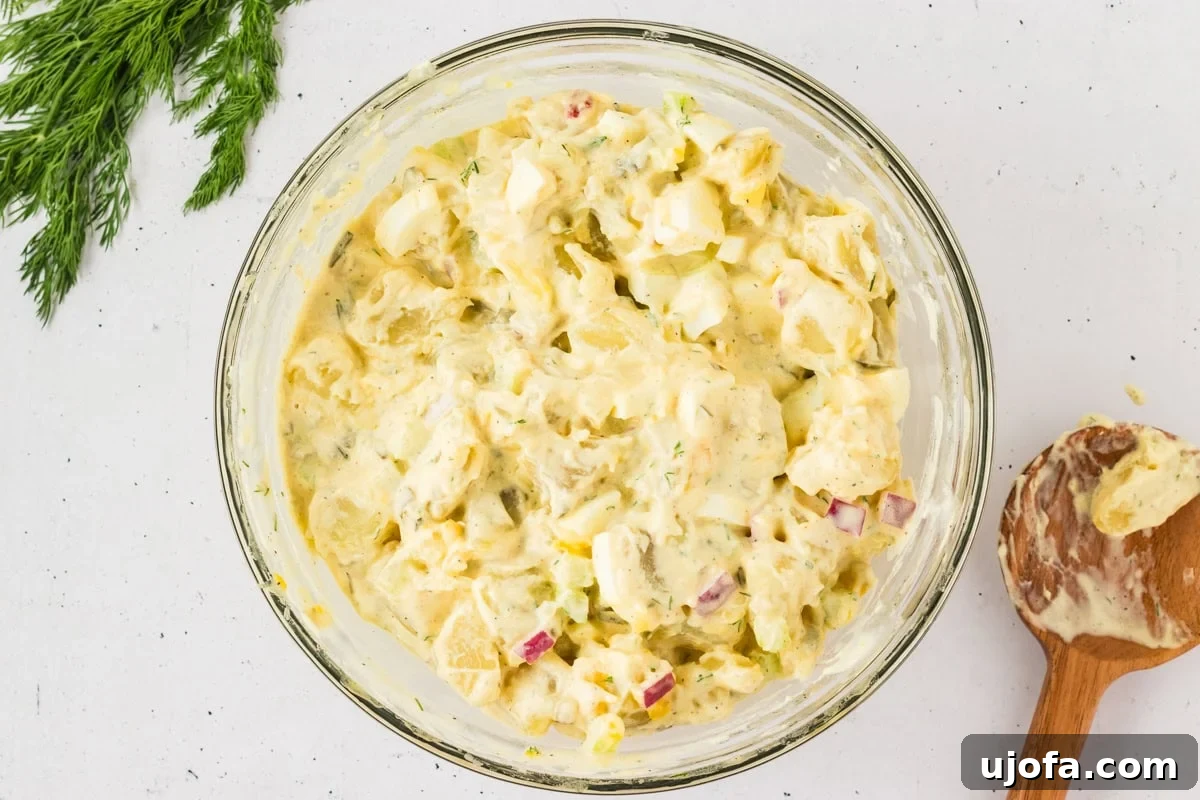 A large bowl of gluten-free potato salad, featuring a creamy texture with diced potatoes, eggs, celery, and red onions.